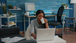 woman at laptop drinking coffee in the office